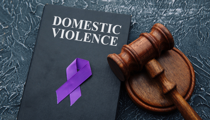 Domestic violence law and gavel on grey table with violet ribbon on top of the book