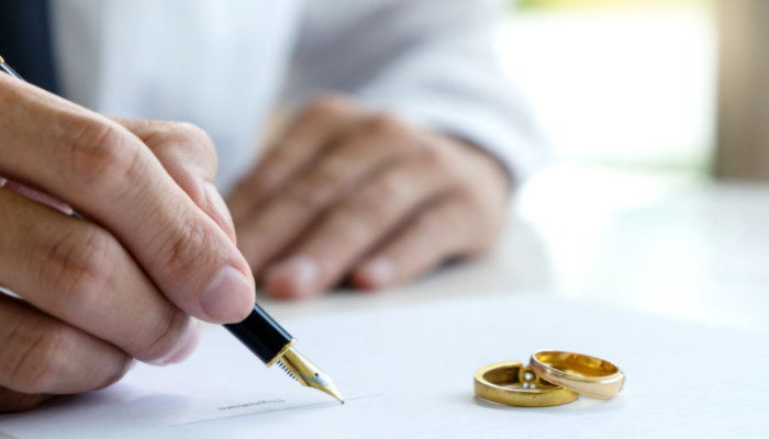 Hand of man with white shirt on paper with ring on paper to sign papers