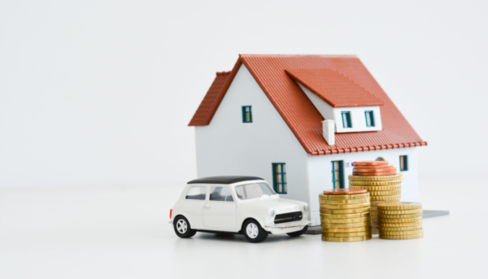 White car and house model with stack of coins isolated on white background, assets concept