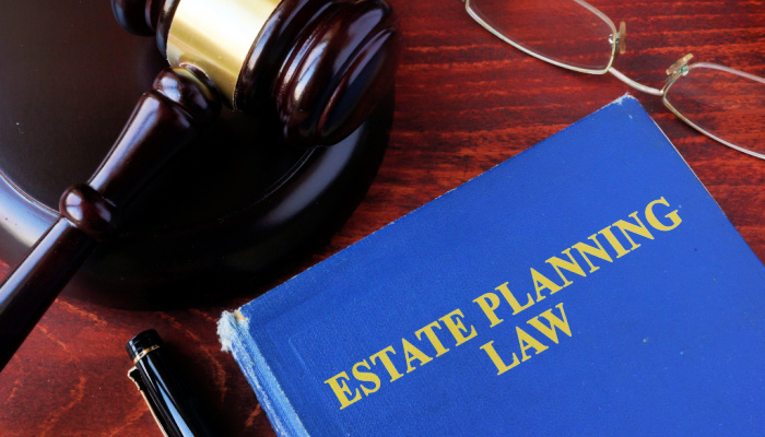 Book with title estate planning law and a gavel on a wooden table